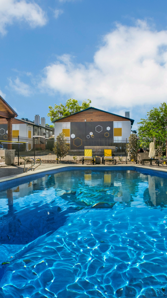 a pool with lounge chairs and umbrellas at The  Hive