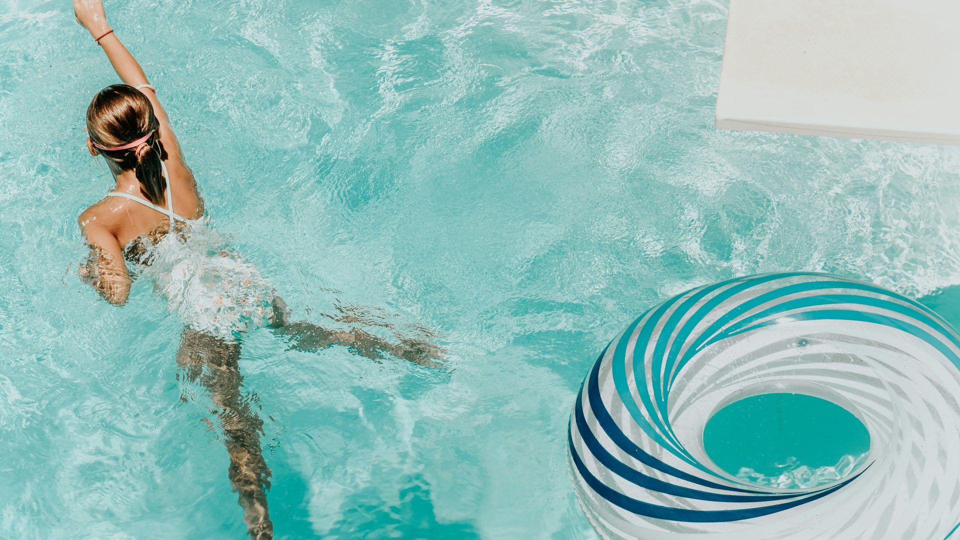 girl wearing swimsuit and swims in swimming pool